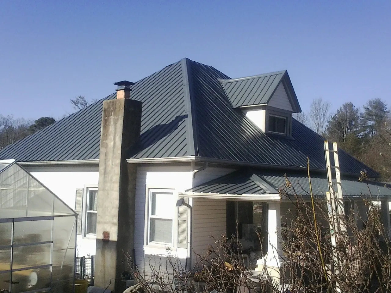 Dark blue standing seam metal roof on a white farmhouse with dormer — Slate & Tile Roof Repair by Roofing Brothers in Mount Perry