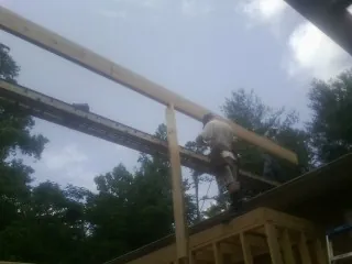 Carpenter setting a ridge beam over a new addition frame — Ice Dam Removal by Roofing Brothers in Mount Perry