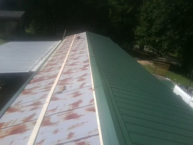 Old rusted panels beside newly installed green metal roofing — Wind Damage Roof Repair by Roofing Brothers in Mount Perry