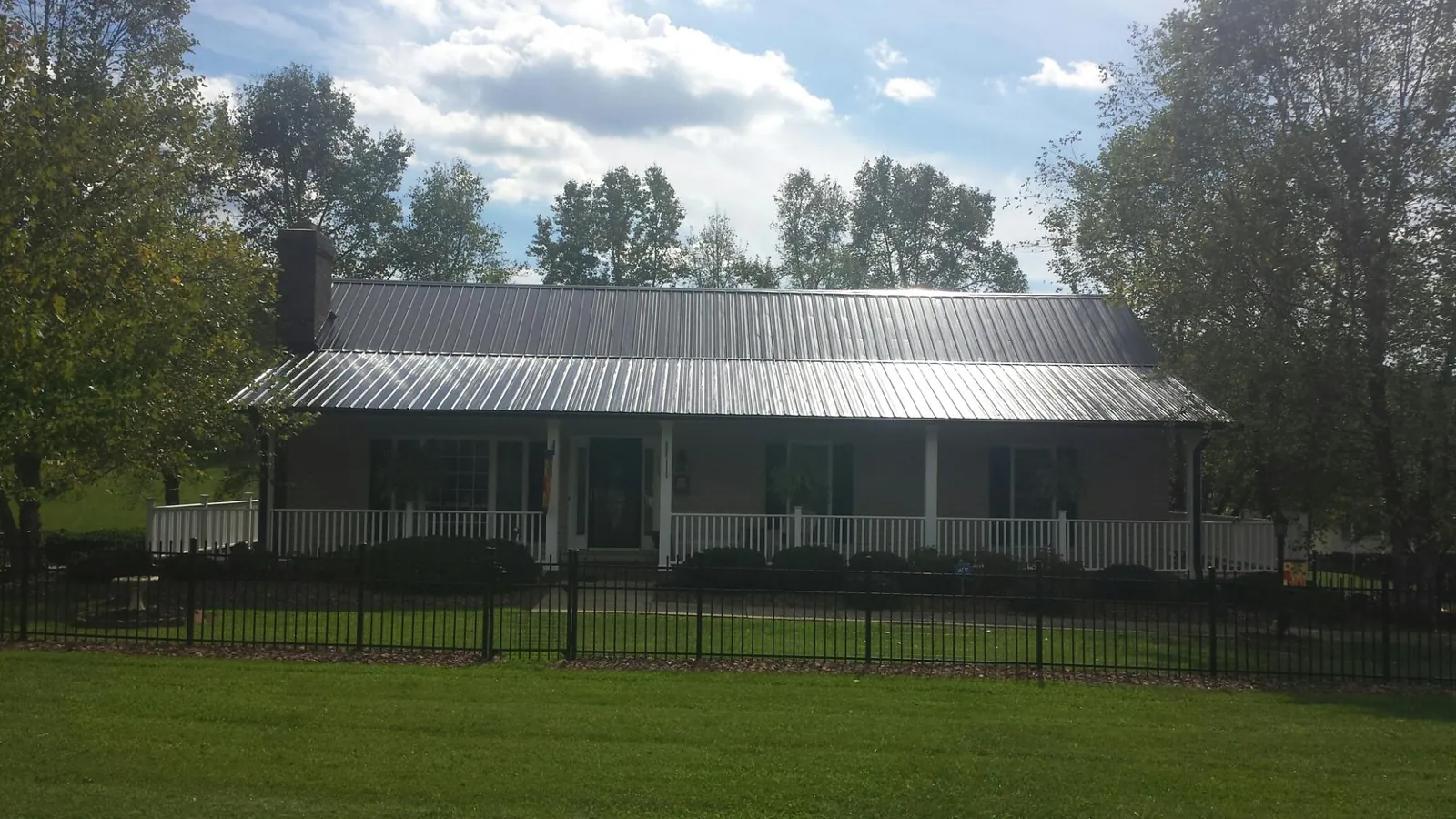 Gray metal roof on a brick ranch with a full width front porch — Gutter Guard Installation work by our crew in Mount Perry