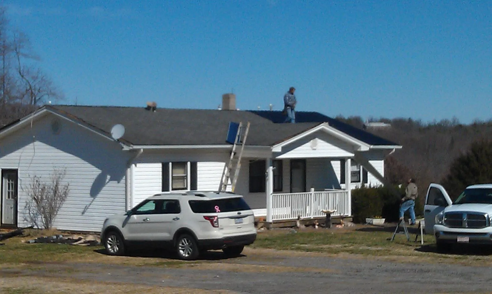 Roofers stripping shingles from a white ranch house roof in Mount Perry