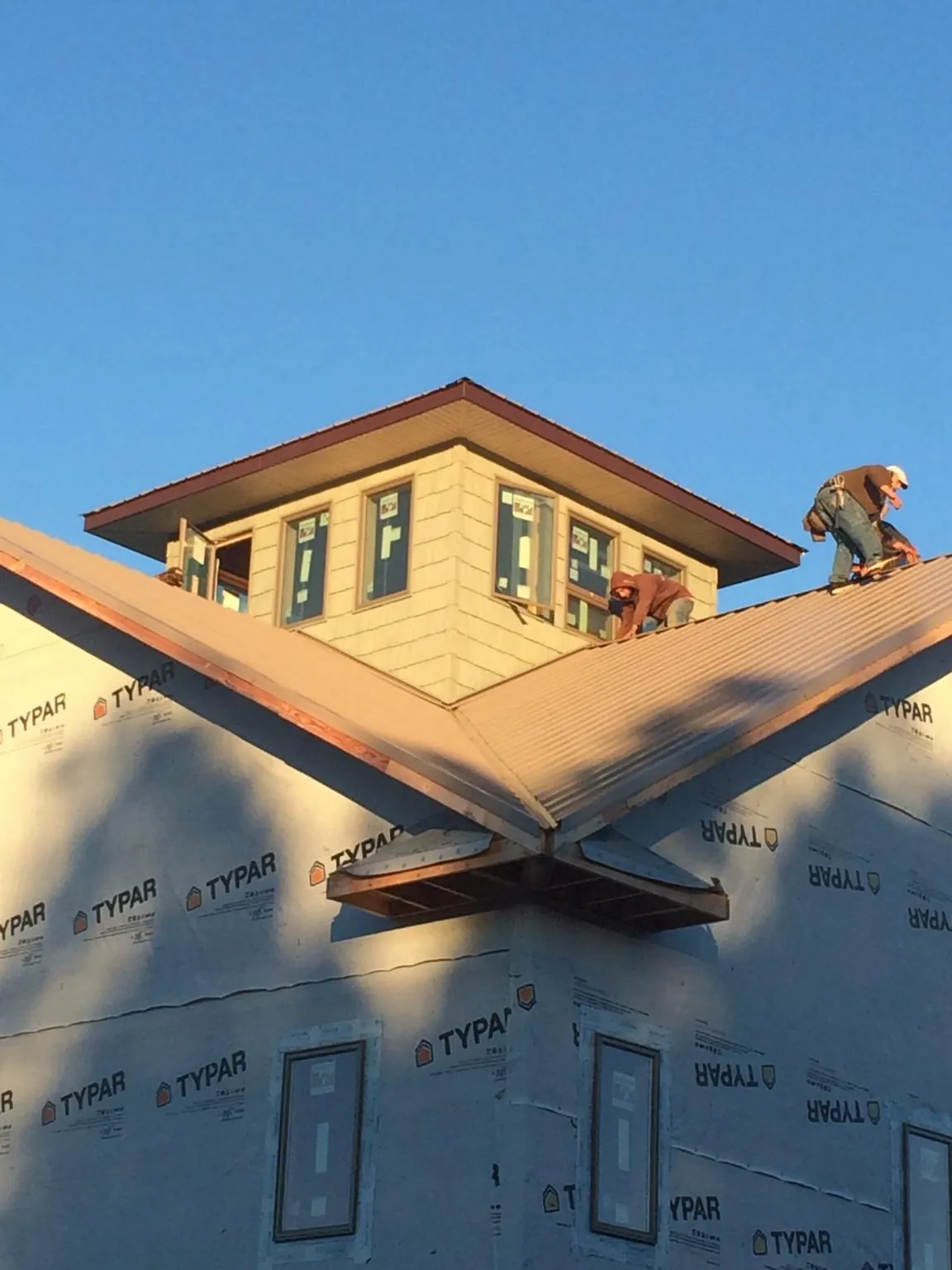 Roofers working around a rooftop cupola on a new metal roof at sunset — Roof Waterproofing in Mount Perry by Roofing Brothers
